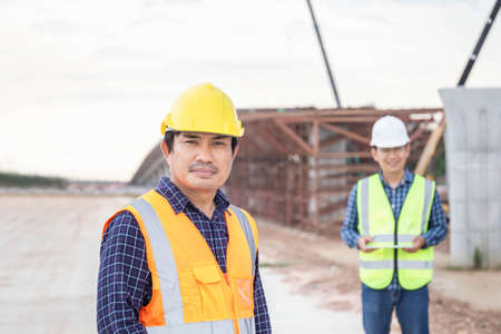 Engineer and foreman worker checking project at building site, Engineer and builders in hardhats in...