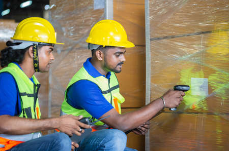 Warehouse workers with bar code scanner checking inventory, Forman worker scanning boxes in warehouse rack, Workers working in warehouseの写真素材