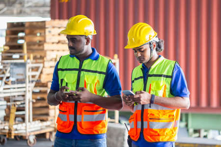 Warehouse worker in the hard hat uses mobile phone, Men using smartphoneの写真素材