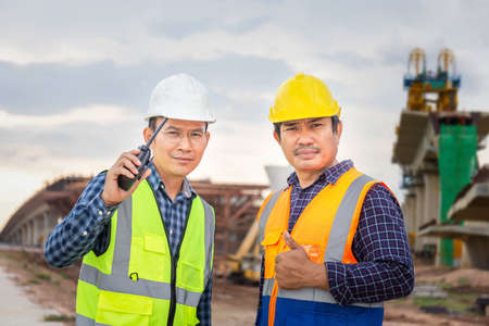 Engineer and foreman worker checking project at building site, Engineer and builders in hardhats discussing on construction site, Teamwork conceptsの写真素材