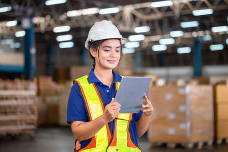 Warehouse worker with digital tablet checking inventory in warehouse, Female warehouse worker working in factory warehouseの写真素材