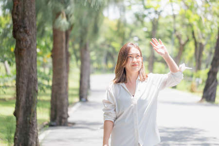 Woman walking in the park having sunstroke in summer hot weather, Young pretty girl drying sweat using a wipe on a warm summer day in a parkの写真素材