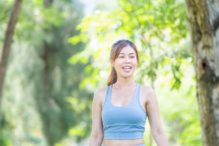 Cheerful sportswoman in the green park, Smile girl exercising outdoors, Healthy lifestyle conceptsの写真素材