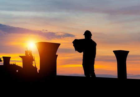 Silhouette of Engineer man checking project at building site background, Infrastructure construction site at sunset in evening timeの写真素材