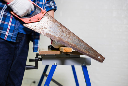 Carpenter sawing a board with a hand wood saw