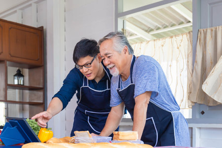 Senior Asian father and middle-aged son cooking together in kitchen, Happiness family and Father's day conceptsの写真素材