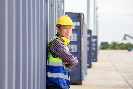 Relaxing engineer man in industry containers cargo, Foreman dock worker in hardhat and safety vest...