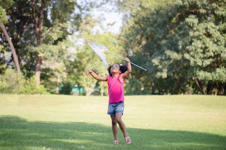 Cute little kid girl playing outdoors in the garden, Black child girl in the parkの写真素材