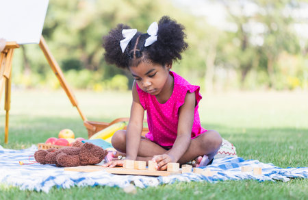 Cute little girl play toy at the garden, Child girl playing with little wooden toy outdoorの写真素材