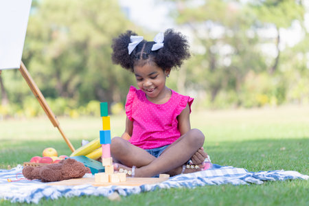 Cute little girl play toy at the garden, Child girl playing with little wooden toy outdoorの写真素材