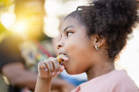 Kid girl with ring pop candy in the park, Girls enjoy ring candy pops, Children play outdoorの写真素材
