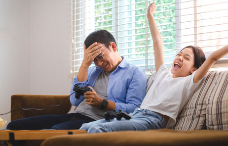 Asian father and daughter playing video games at home, People doing activities and family conceptsの写真素材
