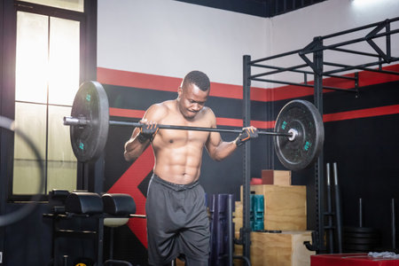 African American fitness man lifting weights in gym fitness, Muscular man working out in gym doing exercises with barbell weightの写真素材