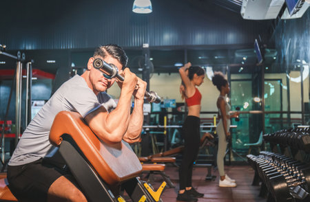 Fitness man lifting weights in gym fitness, Handsome man doing biceps lifting barbell on bench in a gymの写真素材
