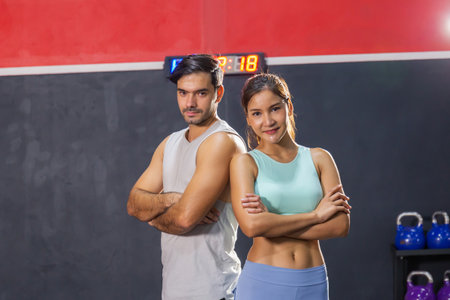 Sporty couple friends standing arms crossed, Young man and woman relaxing in sports outfits at the gym, Sport and fitness conceptsの写真素材