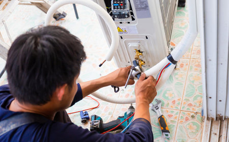 Male technician fixing modern air conditioner, Electrician installing air conditioner unit, Repairman installing an air conditioner unit in a client house, Maintenance and repairing conceptsの写真素材