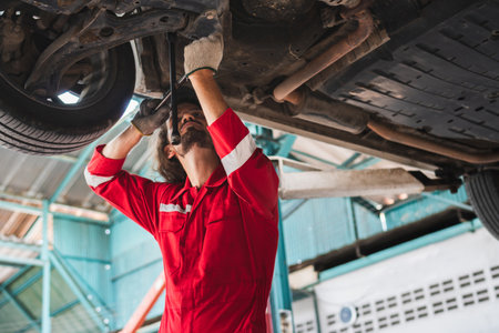 Auto mechanic working in garage, Technician man working in auto service with lifted vehicle, Car repair, and maintenanceの写真素材