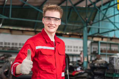 Portrait of a young car mechanic showing thumbs up in repair garage, Car repair and maintenance conceptsの写真素材