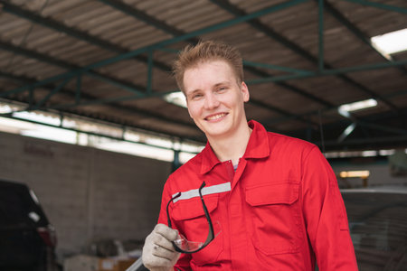 Portrait of a young car mechanic in repair garage, Technician man working in auto repair shop, Car repair and maintenance conceptsの写真素材