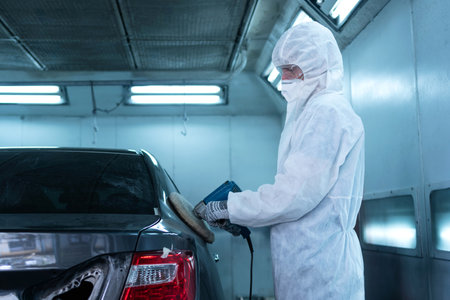 Mechanic man works with grinding tool. Sanding of car elements. Garage painting car service repair and maintenanceの写真素材