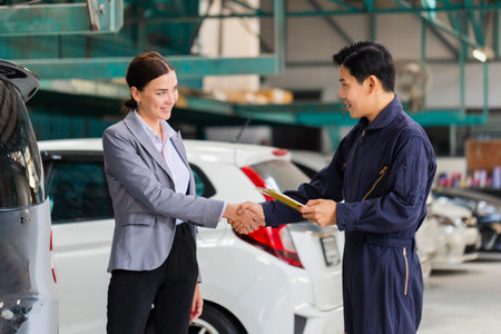 Mechanic man shaking hands with customer at the repair garage. Auto mechanic shaking hands with young woman client, Car repair and maintenance conceptsの写真素材