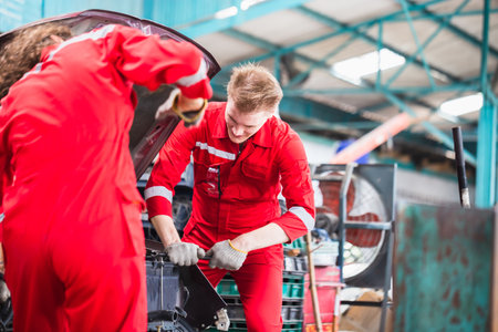 Mechanics in uniform are working in auto service, Technician checking modern car at garage, Car repair and maintenance conceptsの写真素材