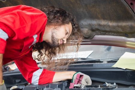 Technician checking modern car at garage, Young caucasian car mechanic standing by vehicle engine area with hood open, Car repair and maintenance conceptsの写真素材