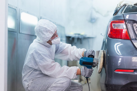 Mechanic man works with grinding tool. Sanding of car elements. Garage painting car service repair and maintenanceの写真素材