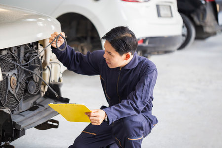 Car mechanic with a checklist, Technician checking modern car at garage, Car repair and maintenance conceptsの写真素材