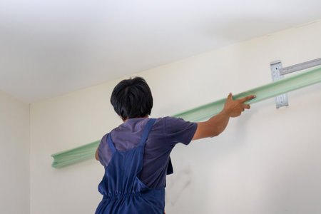 Young repairman fixing air conditioner unit, Asian technician man installing an air conditioning in a client house, Maintenance and repairing conceptsの写真素材