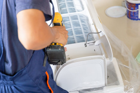 Technician man installing air conditioning in a client house, Young repairman fixing air conditioner unit, Maintenance and repairing conceptsの写真素材