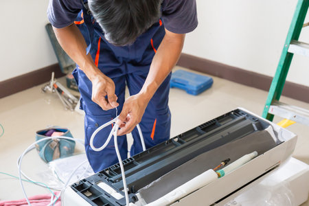 Technician man installing air conditioning in a client house, Young repairman fixing air conditioner unit, Maintenance and repairing conceptsの写真素材