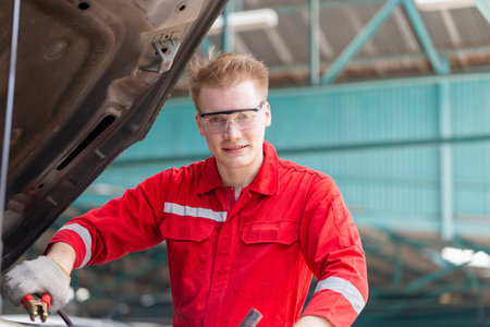 Technicians man with charging cables for car battery, Auto mechanic working in garage, Technician working in auto service, Car repair, and maintenanceの写真素材