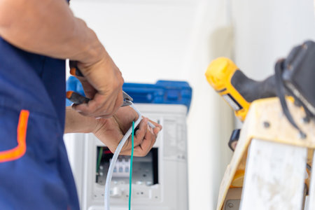 Technician man installing air conditioning in a client house, Young repairman fixing air conditioner unit, Maintenance and repairing conceptsの写真素材