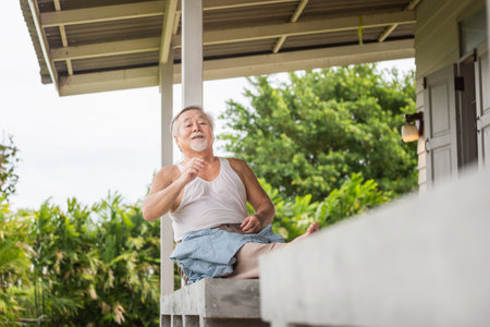 Senior Asian man sitting relax on the terrace, Asian elder man sitting at the balconyの写真素材