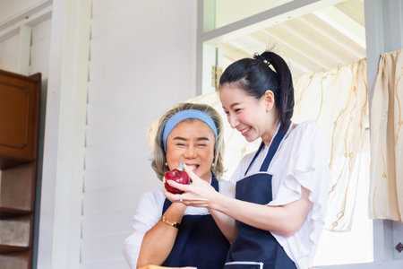 Senior asian mother and middle aged daughter cooking together at kitchenの写真素材