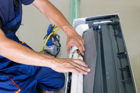 Technician man installing an air conditioning in a client house, Young repairman fixing air conditioner unit, Maintenance and repairing conceptsの写真素材