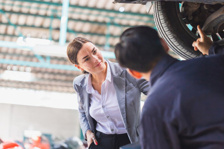 Female manager and auto mechanic in auto repair shop, Mechanic and young woman client talking together at the repair garage, Car repair and maintenanceの写真素材