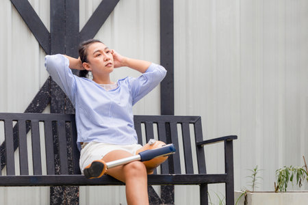 Women with disability with prosthetic legs sitting relax outdoors at home. Woman relaxing in the backyardの写真素材