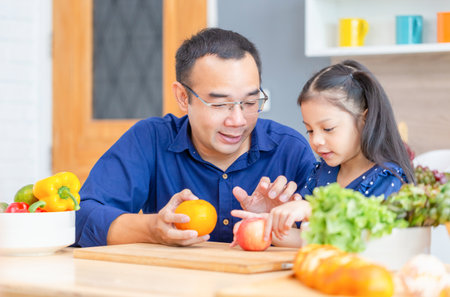 Father and daughter cooking together, Father is teaching his daughter to cook for breakfast in kitchen, Happy family conceptsの写真素材