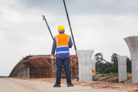 Rear view of Engineer under inspection and checking project at the building site, Foreman worker in hardhat at the infrastructure construction siteの写真素材