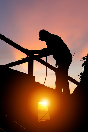 Silhouette of welder worker on building site, construction site at sunset in evening timeの写真素材