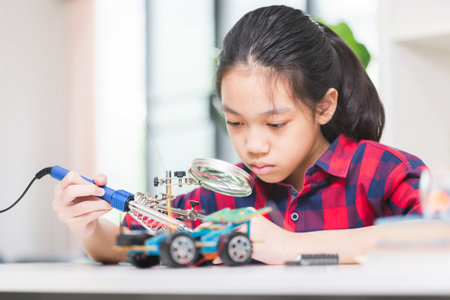 Child girl student build robotic cars, kid learning programming robot vehicles