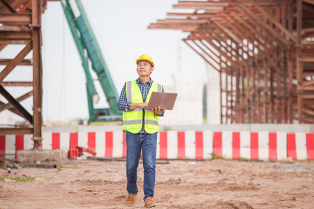 Engineer man with laptop at construction site, Foreman worker checking project in building siteの写真素材