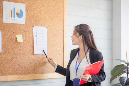 Portrait of Asian woman making a presentation in front of board, Young female employee explains business data on board in the office meeting roomの写真素材