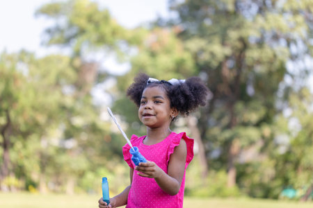 Happy kid girl playing with soap bubbles. Active child playing outdoors in the parkの写真素材
