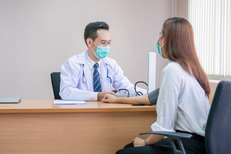 Doctor using sphygmomanometer checks blood pressure of a patient, doctor checking blood pressureの写真素材