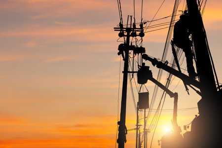 Silhouette of Electrician officer climbs a pole and uses a cable car to maintain a high voltage line...