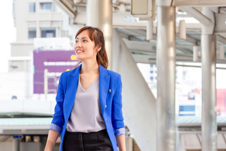 Smiling Asian urban business woman walking outside office