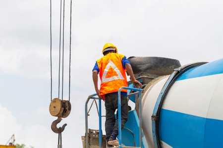 Worker man on concrete mixer trucks at construction siteの写真素材